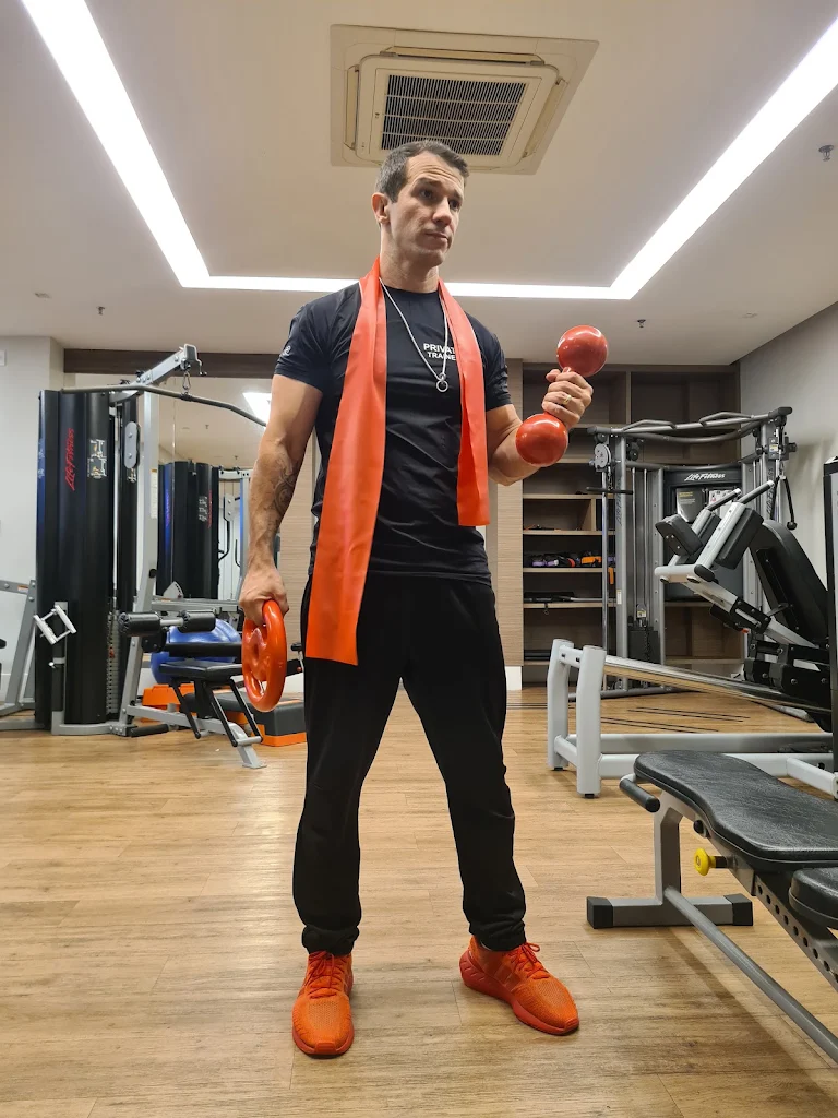 Gustavo Oliveira em academia segurando halter e anilha